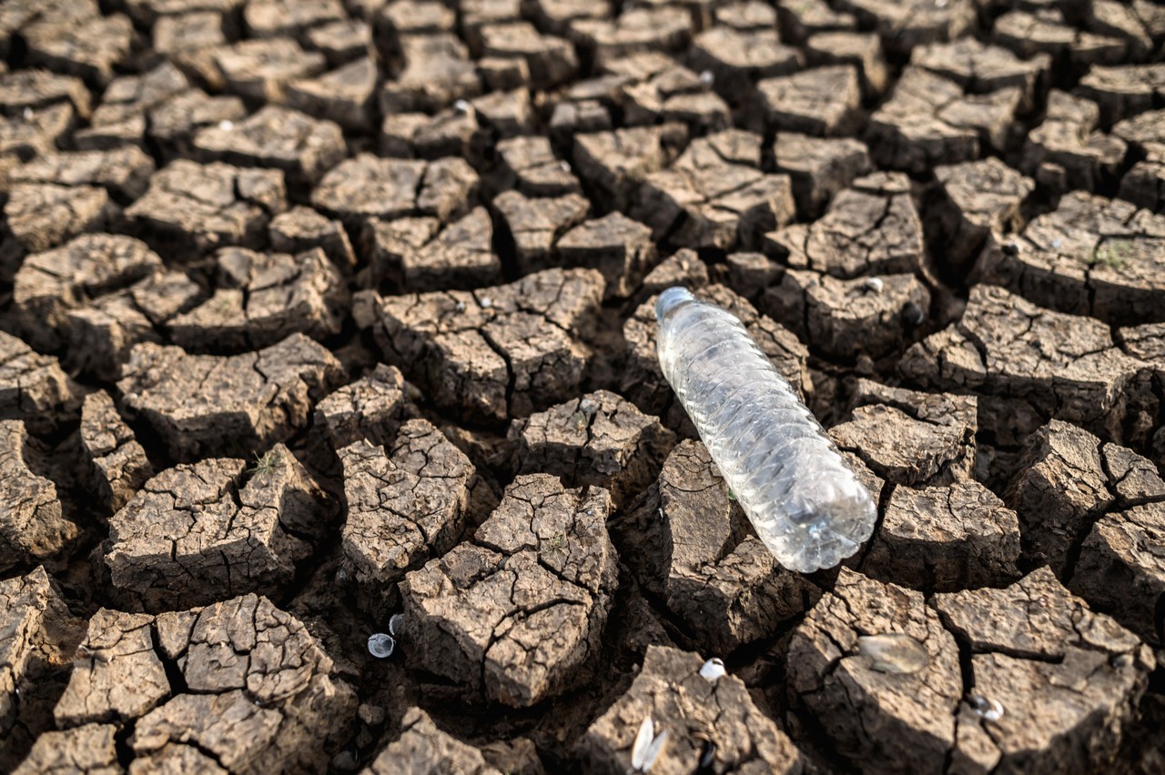 Completely dry and cracked floor with a plastic water bottle on top